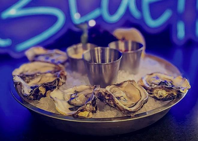 Close-up of oysters on the half shell arranged on ice around cups of sauce
