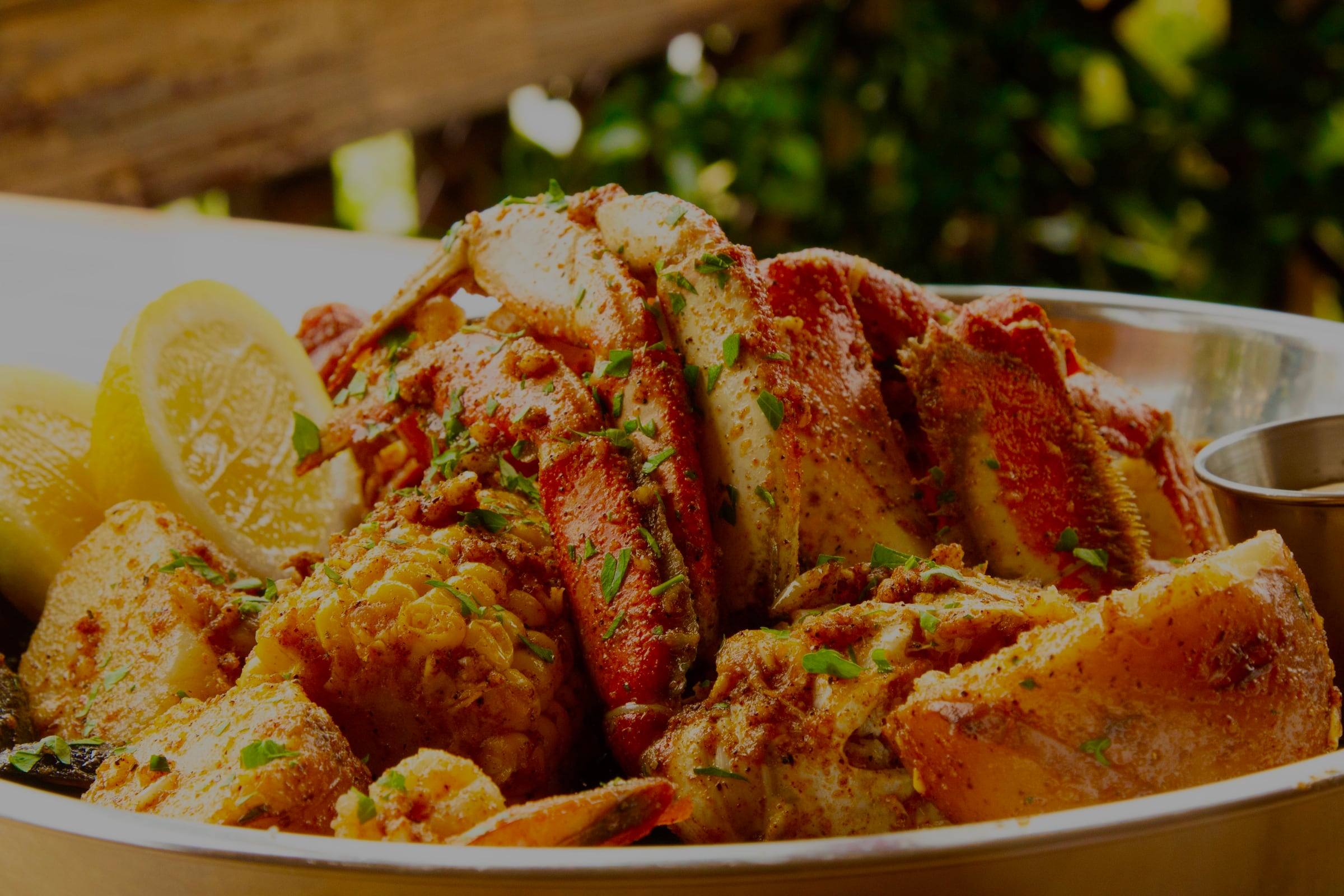 Cajun seafood boil piled with crab legs, corn, potatoes and lemon, dusted with spices and fresh herbs